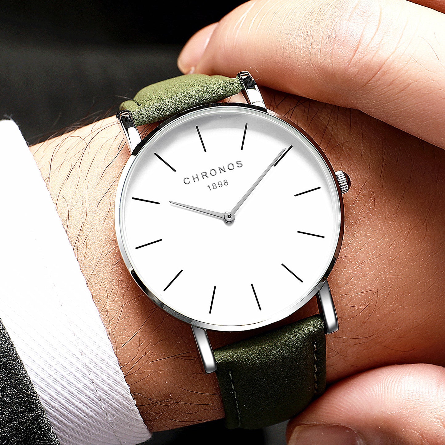 Hand wearing a watch with a green strap and white dial, brand 'Chronos' visible.