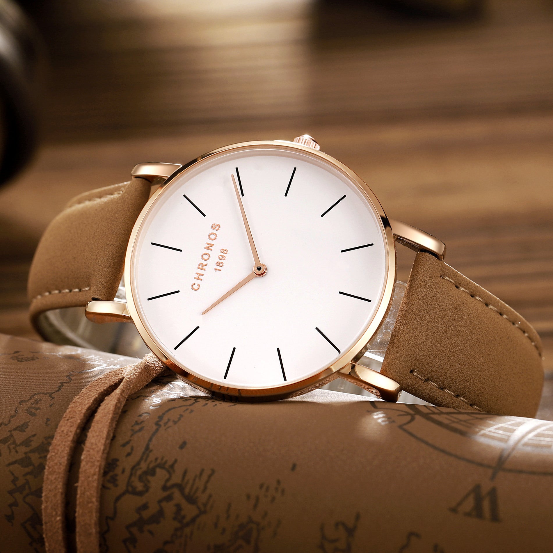 Watch with brown strap and white face on a textured surface