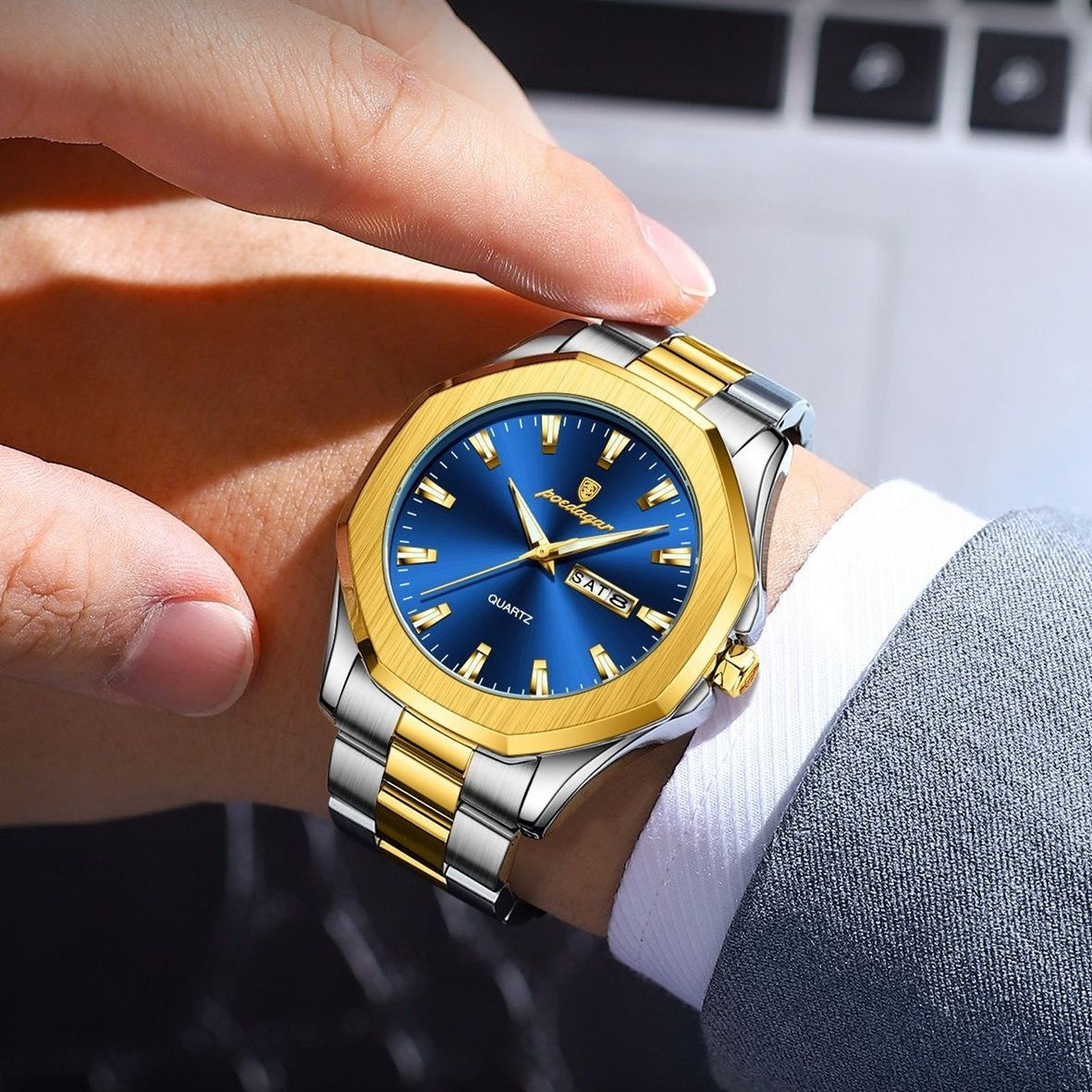 Gold and silver watch with blue face on a wrist, blurred background